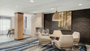 Un comedor moderno con una mesa redonda y seis sillas, una lámpara colgante grande y una pared de acento de piedra.