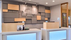 Un'area reception di un hotel con due banchi informazioni, un design moderno della parete e un cartello con scritto 'Huntingdon Express'.