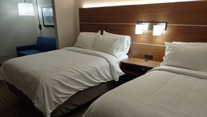 A hotel room with two beds, a wooden headboard, a nightstand, and a blue chair.