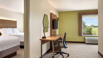 A hotel room with a bed, a desk with a chair, a television, and a window with a view of the outdoors.