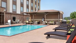 A swimming pool with lounge chairs and a covered seating area.