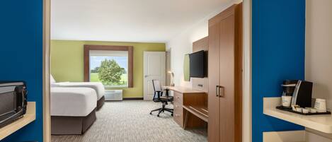 A hotel room with a bed, desk, chair, TV, and coffee maker.