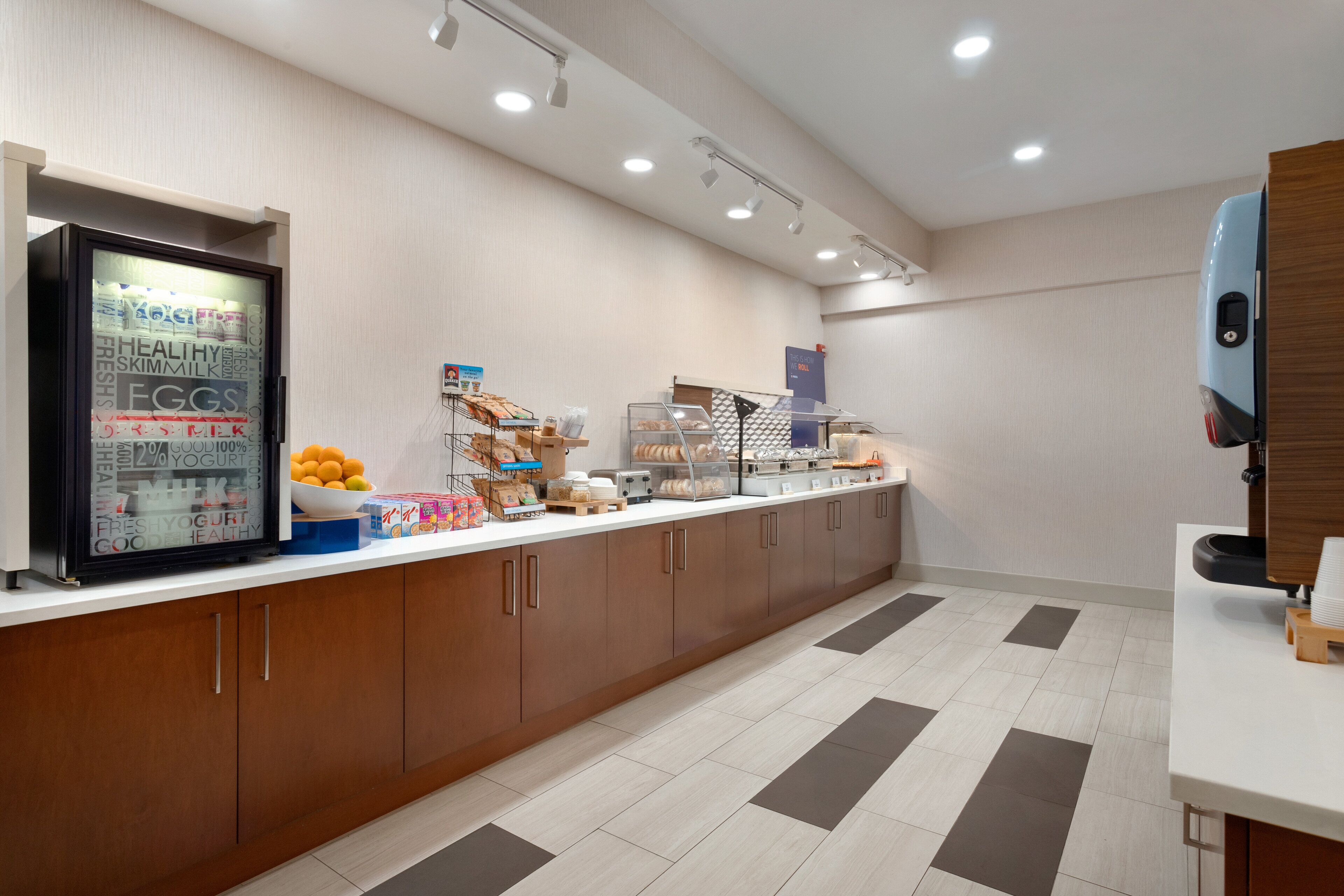A modern breakfast bar with a refrigerated display, a variety of food items, and a coffee station.