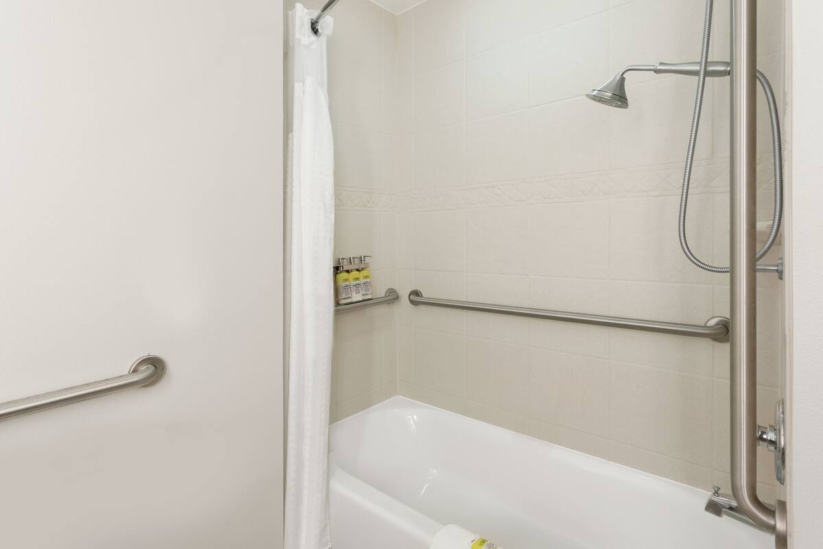 Une salle de bain équipée d’une baignoire, d’une douche et de barres d’appui.