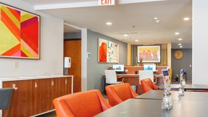 A conference room with a long table, orange chairs, a reception desk, and an exit sign. - Holiday Inn Express Hotel & Suites, a Lake Zurich-Barrington by IHG (Lake Zurich)