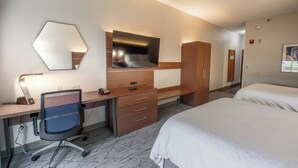 Une chambre d’hôtel équipée d’un bureau, d’une chaise, d’un lit, d’une armoire et d’un miroir.