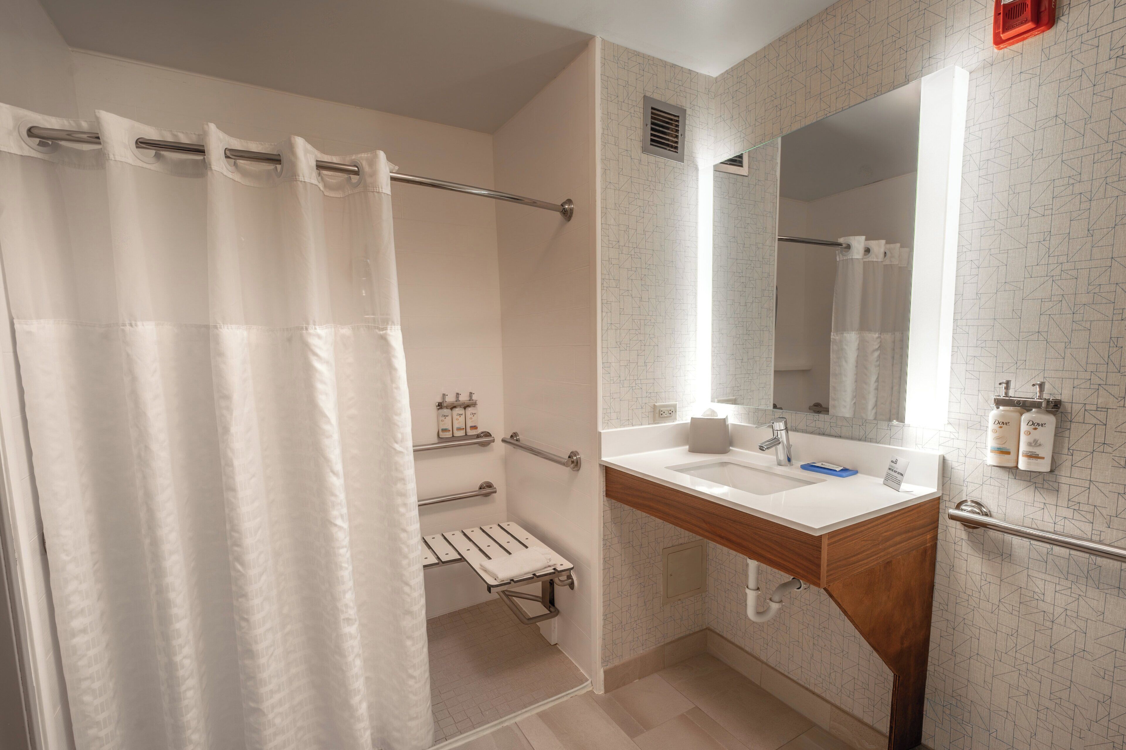 Un baño con cortina de ducha, lavamanos, espejo y toallero.