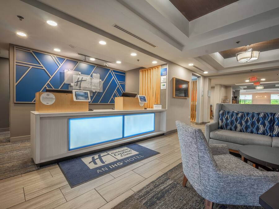 A hotel reception area with a modern design, including a reception desk, seating area, and a visible exit sign.