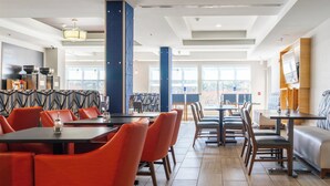 Un espace de restauration moderne avec des tables et des chaises hautes, un pilier central et une vue dégagée grâce à de grandes fenêtres.