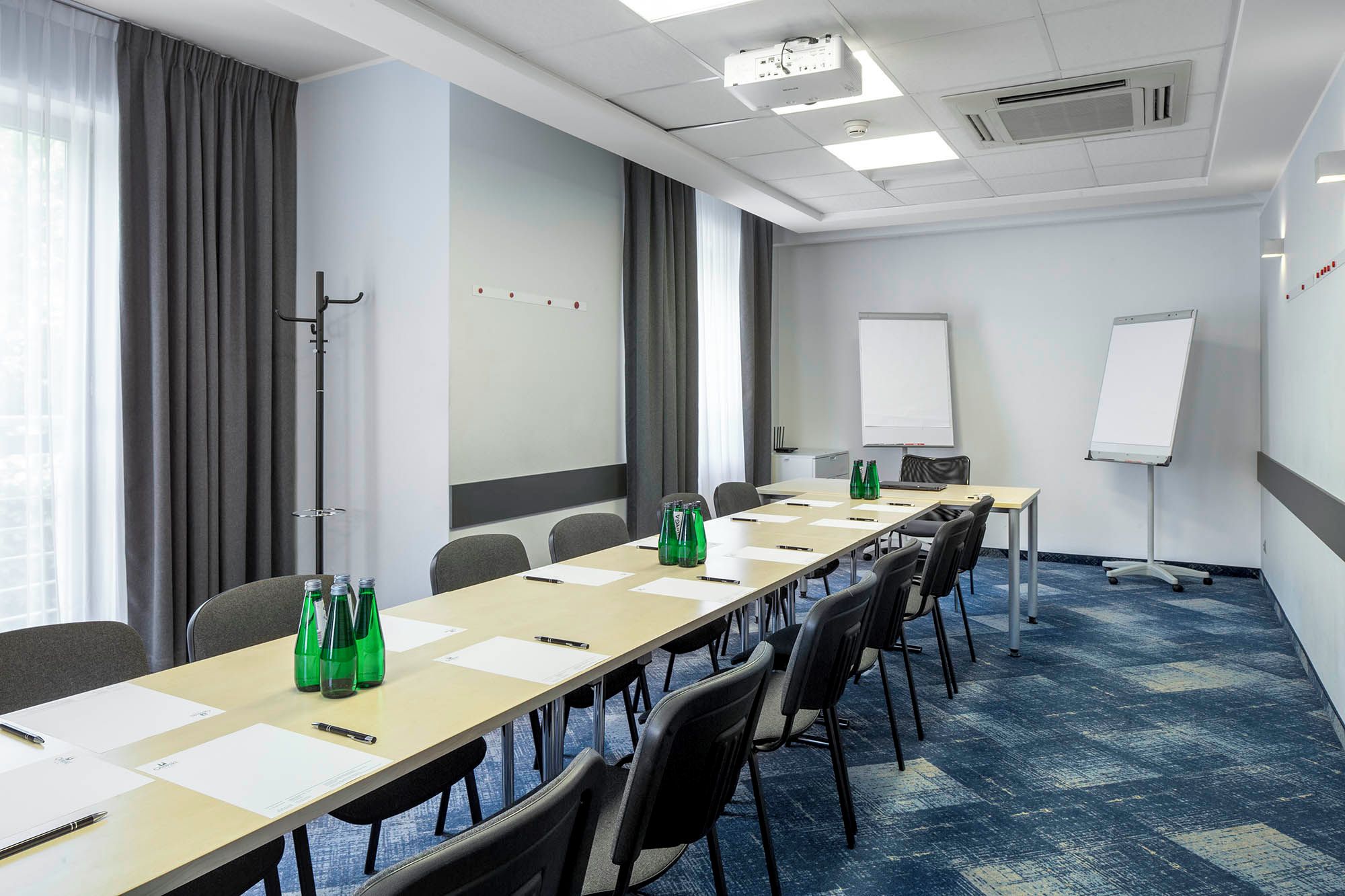 A conference room with a long table, chairs, a whiteboard, and a projector.