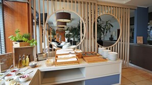 Disposición de bufé con diferentes alimentos, utensilios, un espejo y un panel de madera.