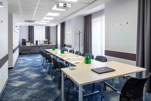 A conference room with a long table, chairs, a projector, and a water dispenser.