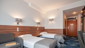 Una habitación de hotel con dos camas individuales, un sofá, un escritorio y una silla.