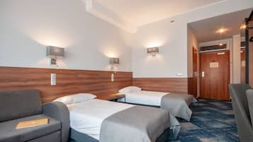 Una habitación de hotel con dos camas individuales, un sofá, un escritorio y una silla.