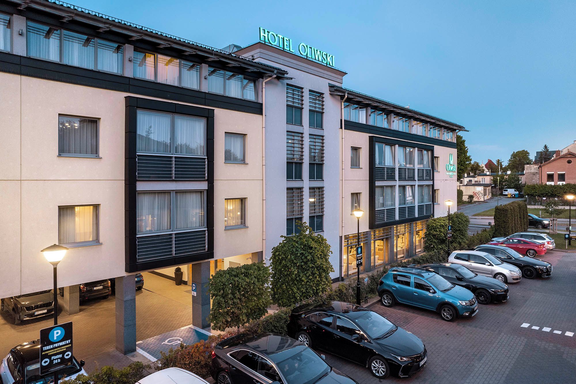 Un hotel con fachada moderna, varios espacios de estacionamiento y cielo despejado.