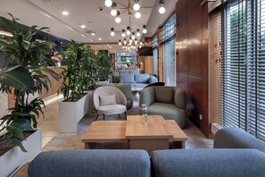 A modern lounge area with seating, a coffee table, and potted plants. - Hotel Oliwski (Gdansk)