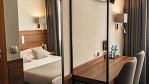 Una habitación de hotel con cama, mesita de noche, lámpara y un escritorio con sillas.