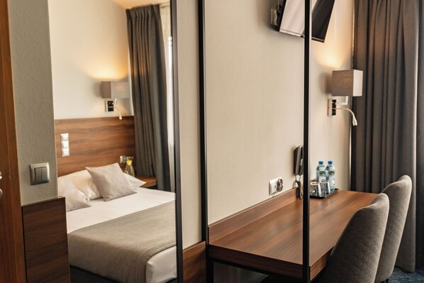 A hotel room with a bed, bedside table, lamp, and a desk with chairs. - Hotel Oliwski (Gdansk)