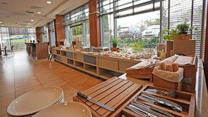 Un restaurante con una barra larga, mesas de madera y vista a coches estacionados afuera.