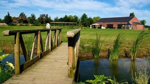 A wooden bridge over a pond leading to a brick building with a covered area and a white structure in the background. - Brackenborough Hotel, BW Signature Collection (Louth)