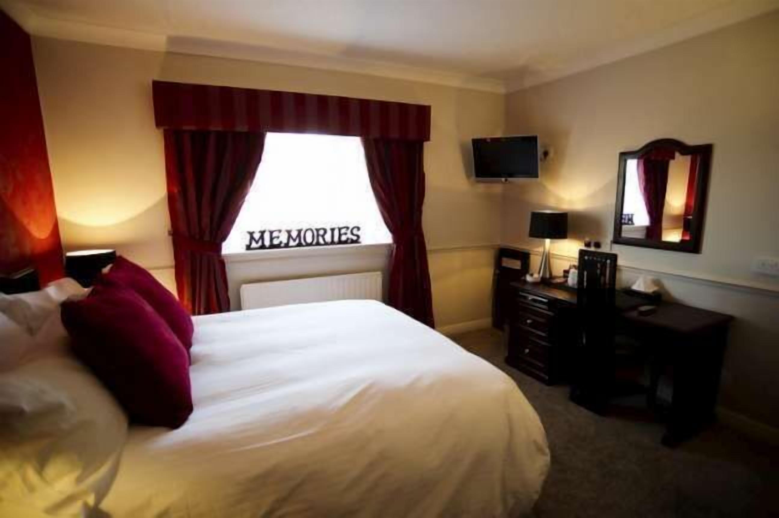 Una habitación de hotel con cama, televisor, cómoda y espejo.
