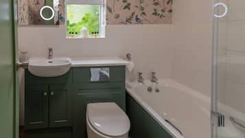 A bathroom with a white sink, green cabinets, a white toilet, and a bathtub.
