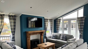 A modern living room with a fireplace, grey sofas, a wooden coffee table, and a flat-screen TV mounted on the wall. - Brackenborough Hotel, BW Signature Collection (Louth)