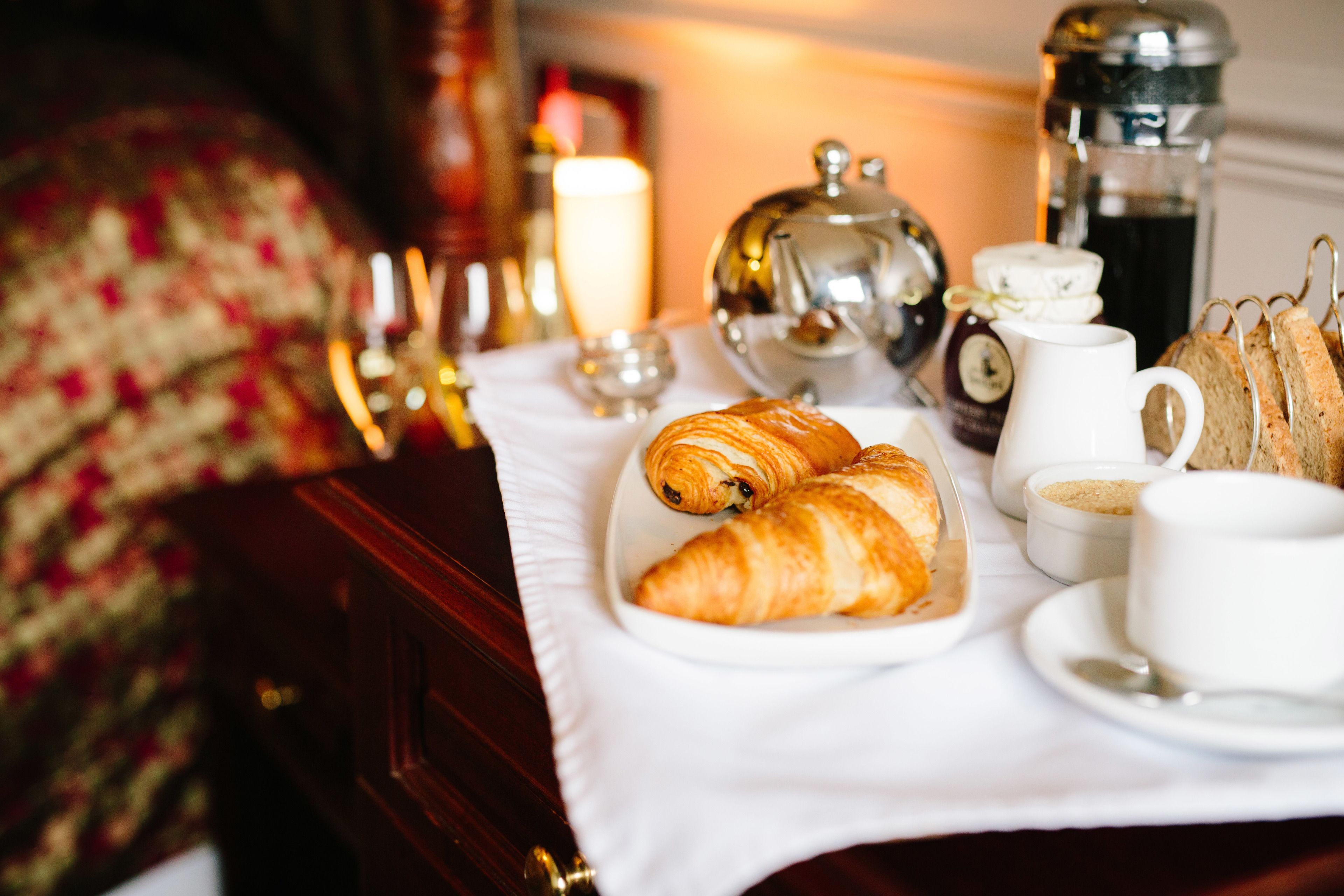 A breakfast setup with croissants, coffee, and tea on a table.