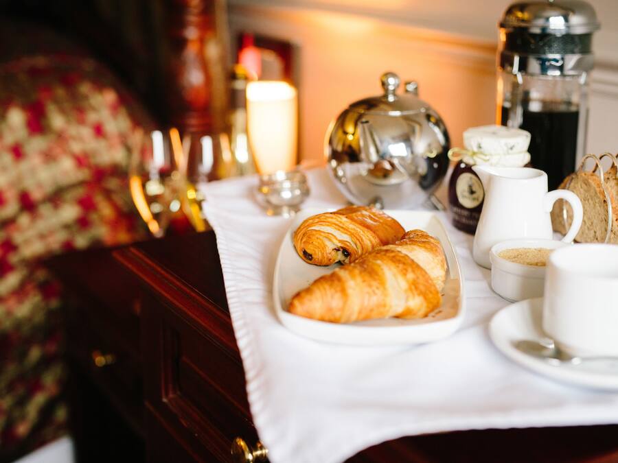 A breakfast setup with croissants, coffee, and tea on a table.