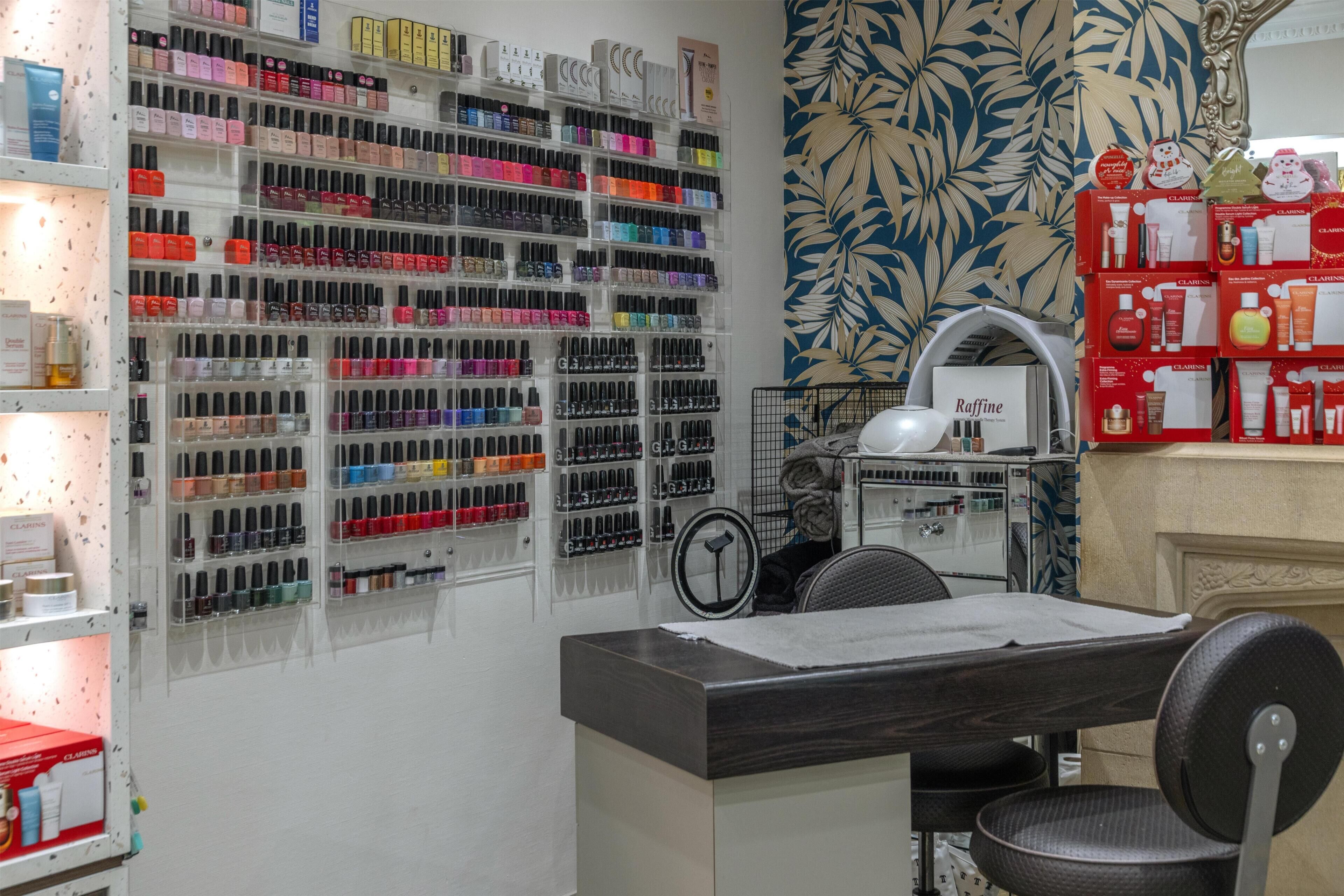 Een nagelsalon met meerdere planken vol nagellak, een spiegel en een toonbank met een stoel.
