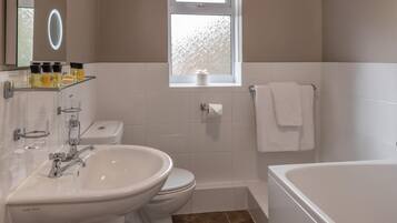 A bathroom with a sink, toilet, bathtub, and a window with frosted glass.