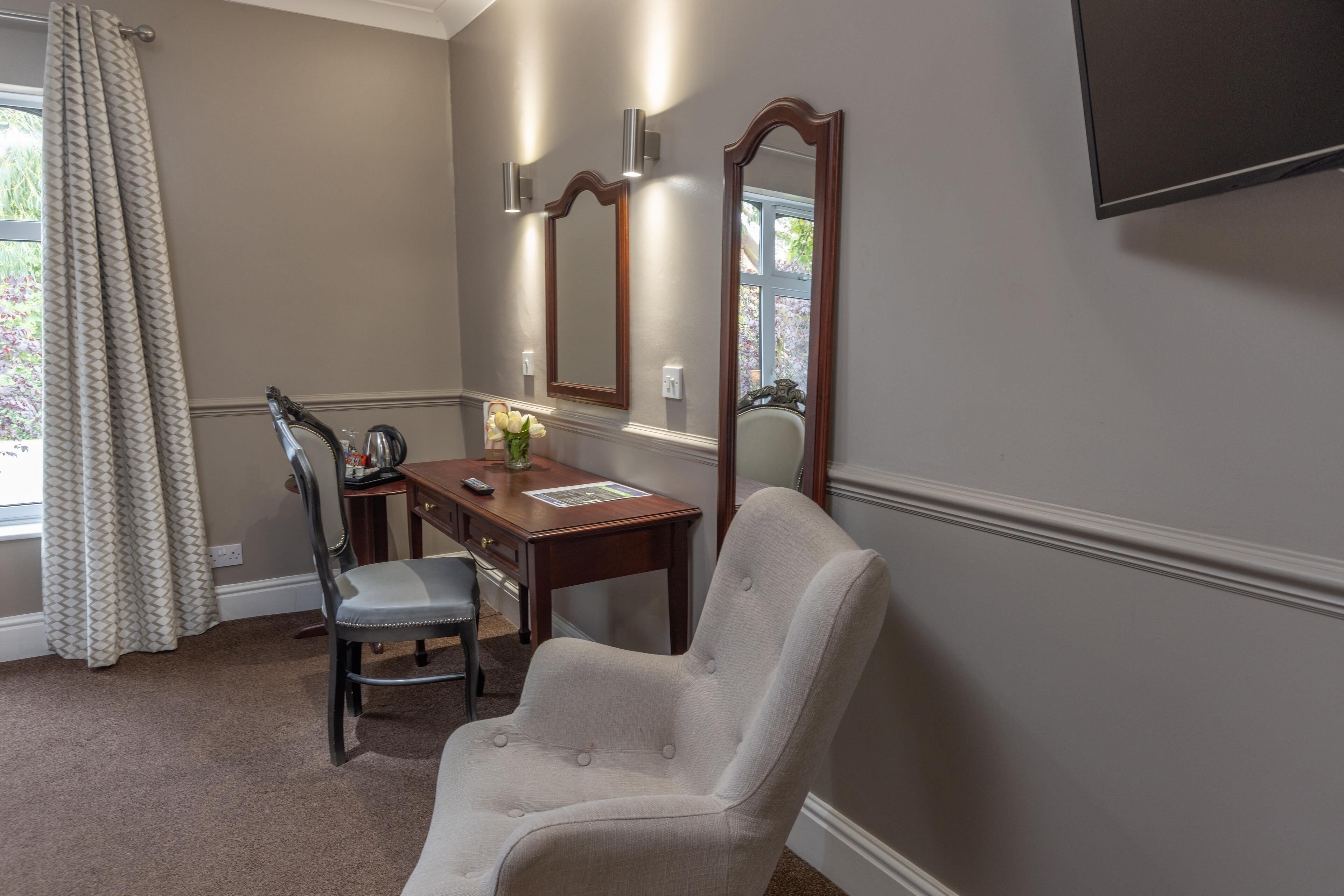 A room with a desk, chair, and a large mirror.
