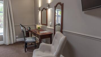 A room with a desk, chair, and a large mirror.