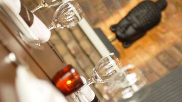 A close-up of wine glasses on a table with a candle and a Buddha statue in the background.