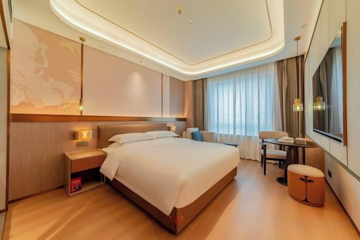 Ein Hotelzimmer mit einem großen Bett, Nachttischen, einem Schreibtisch und einem Sessel.