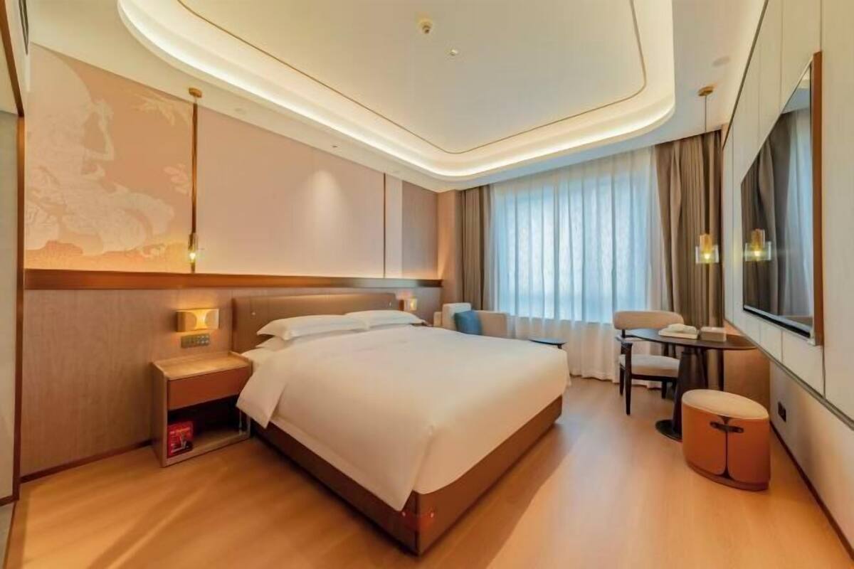 Una habitación de hotel moderna con una cama grande, mesitas de noche, un escritorio y una silla.