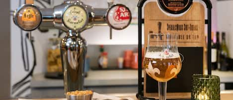 Una grifería con varias opciones de cerveza, una jarra de cerveza y una vela sobre una mesa.