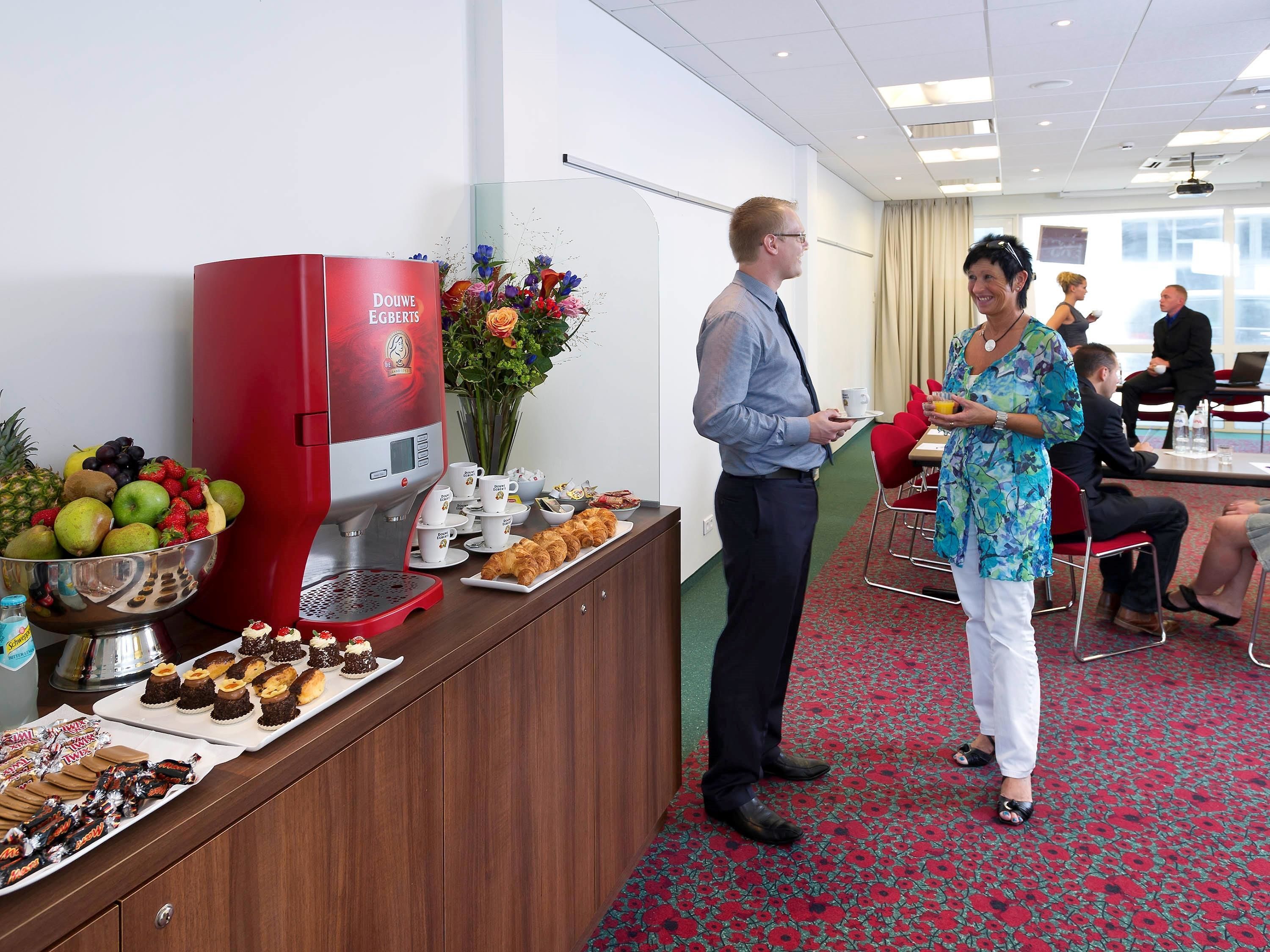 A buffet area with a coffee machine, fruit bowl, and pastries.