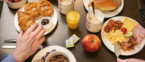 Una escena de desayuno con diversos alimentos y utensilios sobre una mesa.