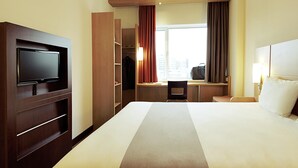 Habitación de hotel con cama, televisión, escritorio y armario.