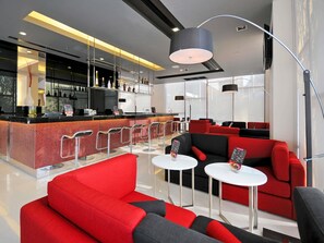 Een moderne bar met een toonbank, zitplaatsen en een grote hanglamp.