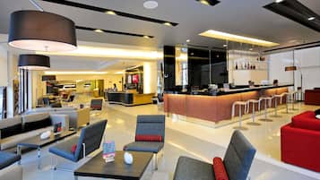 Een moderne hotellobby met zithoeken, een receptiebalie en een bar.