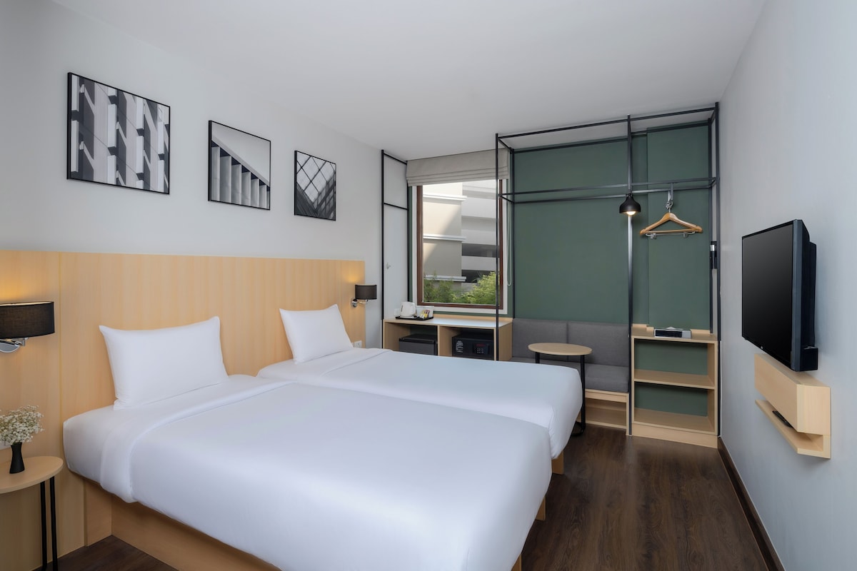 Een moderne hotelkamer met een groot bed, een televisie, een bureau en uitzicht op het omliggende landschap.