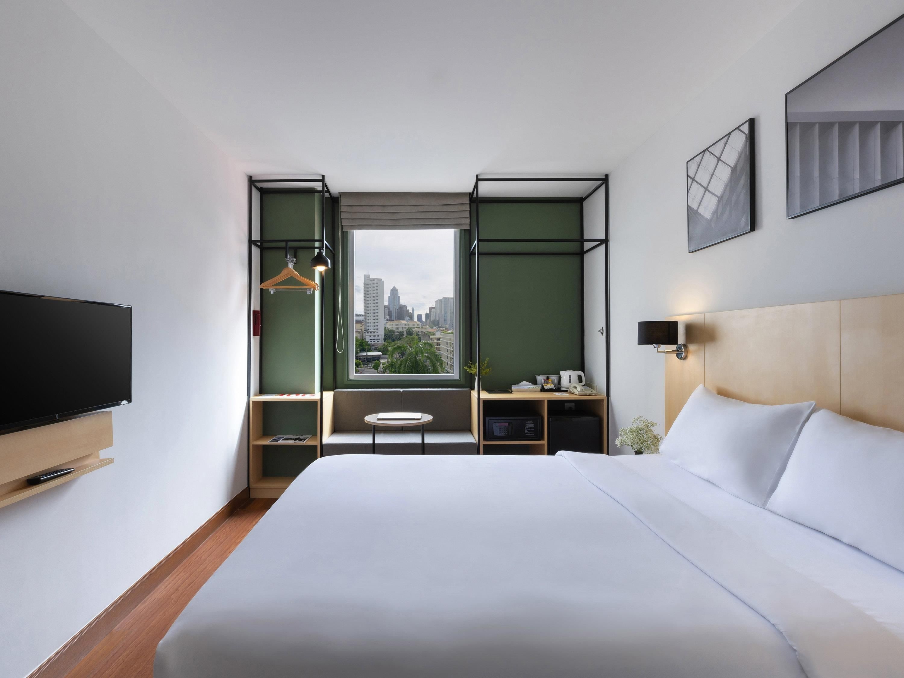 Une chambre d’hôtel moderne dotée d’un grand lit, d’une télévision, d’un bureau et offrant une vue sur la ville.