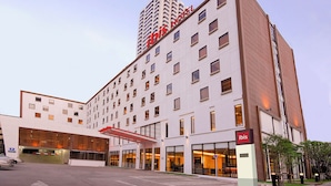 Een modern hotel met een opvallend “ibis HOTEL” bord, meerdere verdiepingen en een ruime entree met overdekt gebied.