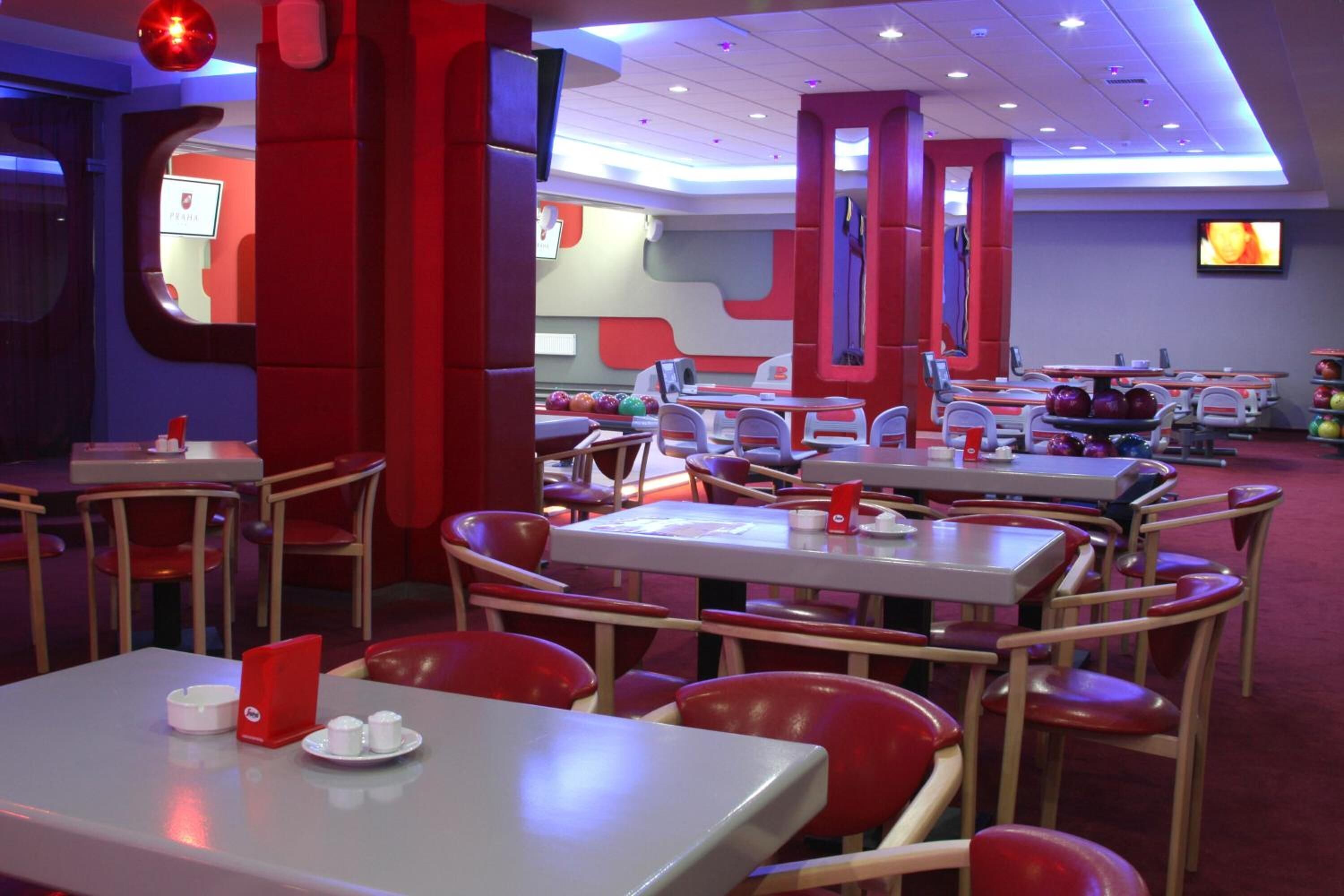 A bowling alley with red and white seating, multiple lanes, and a television screen.