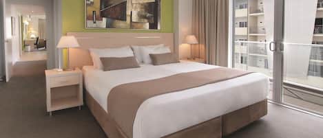 Habitación de hotel con una cama grande, lámparas de noche, un cuadro en la pared y vistas al balcón exterior.