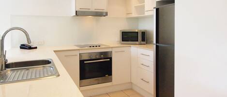 Una cocina moderna con armarios blancos, electrodomésticos de acero inoxidable y piso de baldosas.