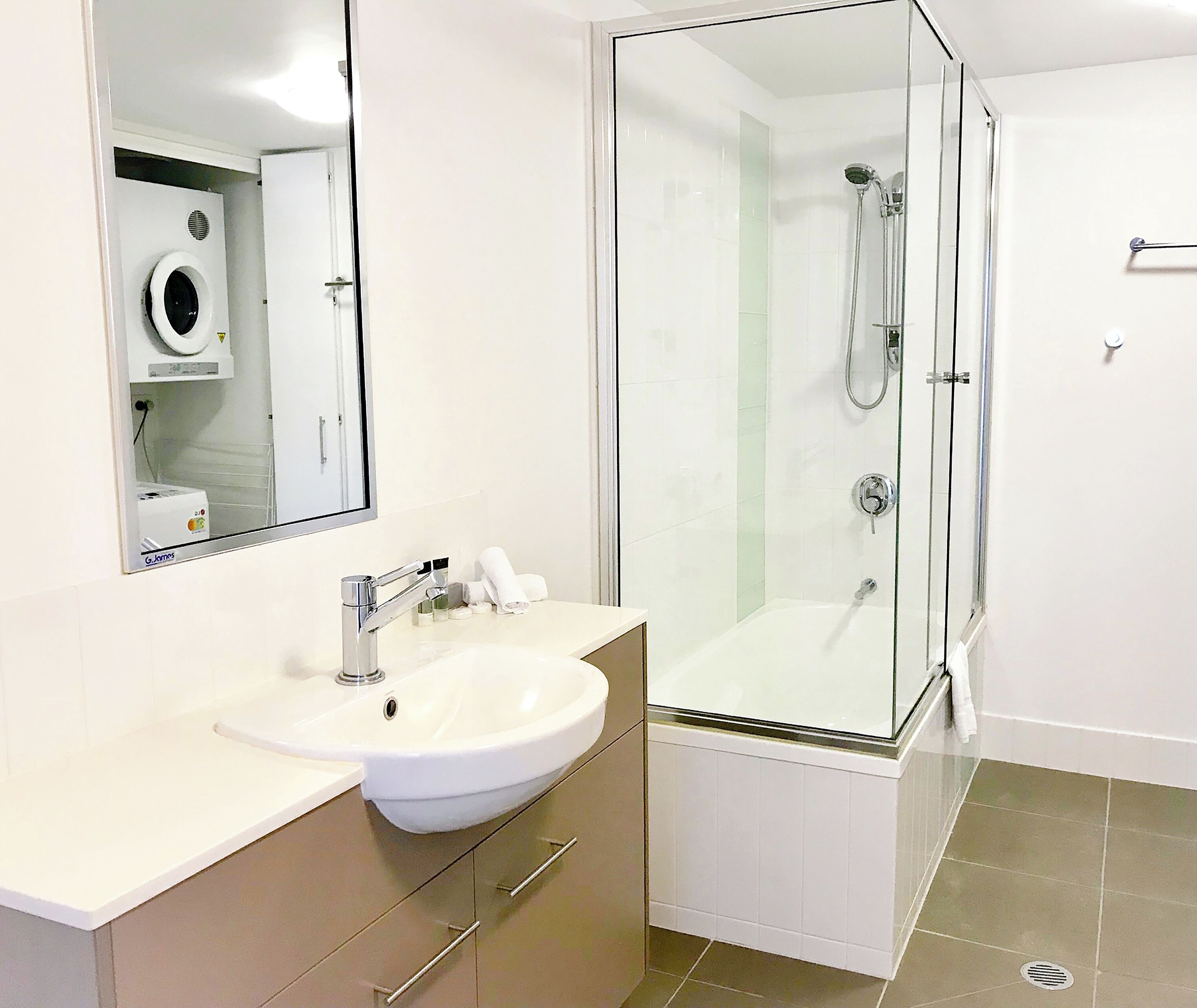 Une salle de bain moderne avec une douche à parois de verre, un lavabo blanc et un miroir au-dessus du lavabo.