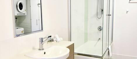 Une salle de bain moderne avec une douche à parois de verre, un lavabo blanc et un miroir au-dessus du lavabo.